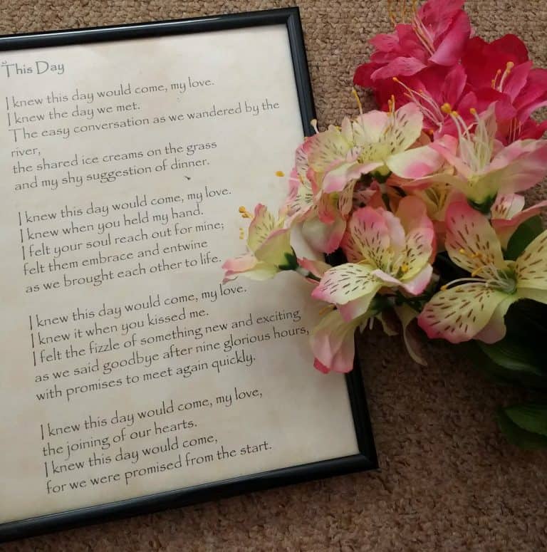 Kiss of love poem with pink and white flowers, framed on a carpeted surface.