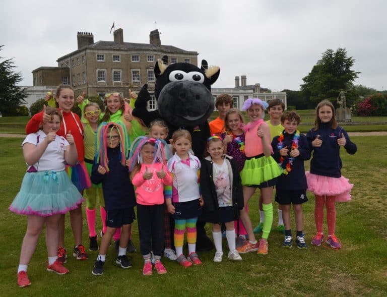 Group of children with mascot at Suffolk Business outdoor event.