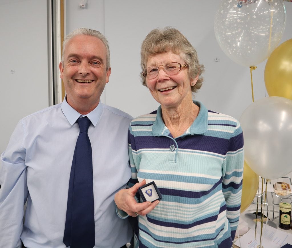 Celebrating achievements with elderly woman and man at Suffolk Business event.