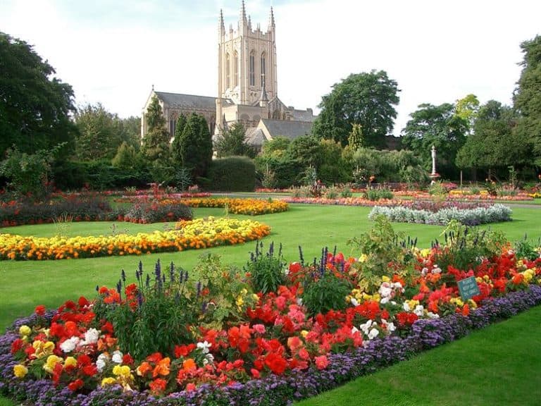 Beautiful Suffolk garden with vibrant flower beds and historic church backdrop.