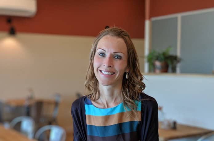 A woman smiling in a modern office environment with warm lighting.