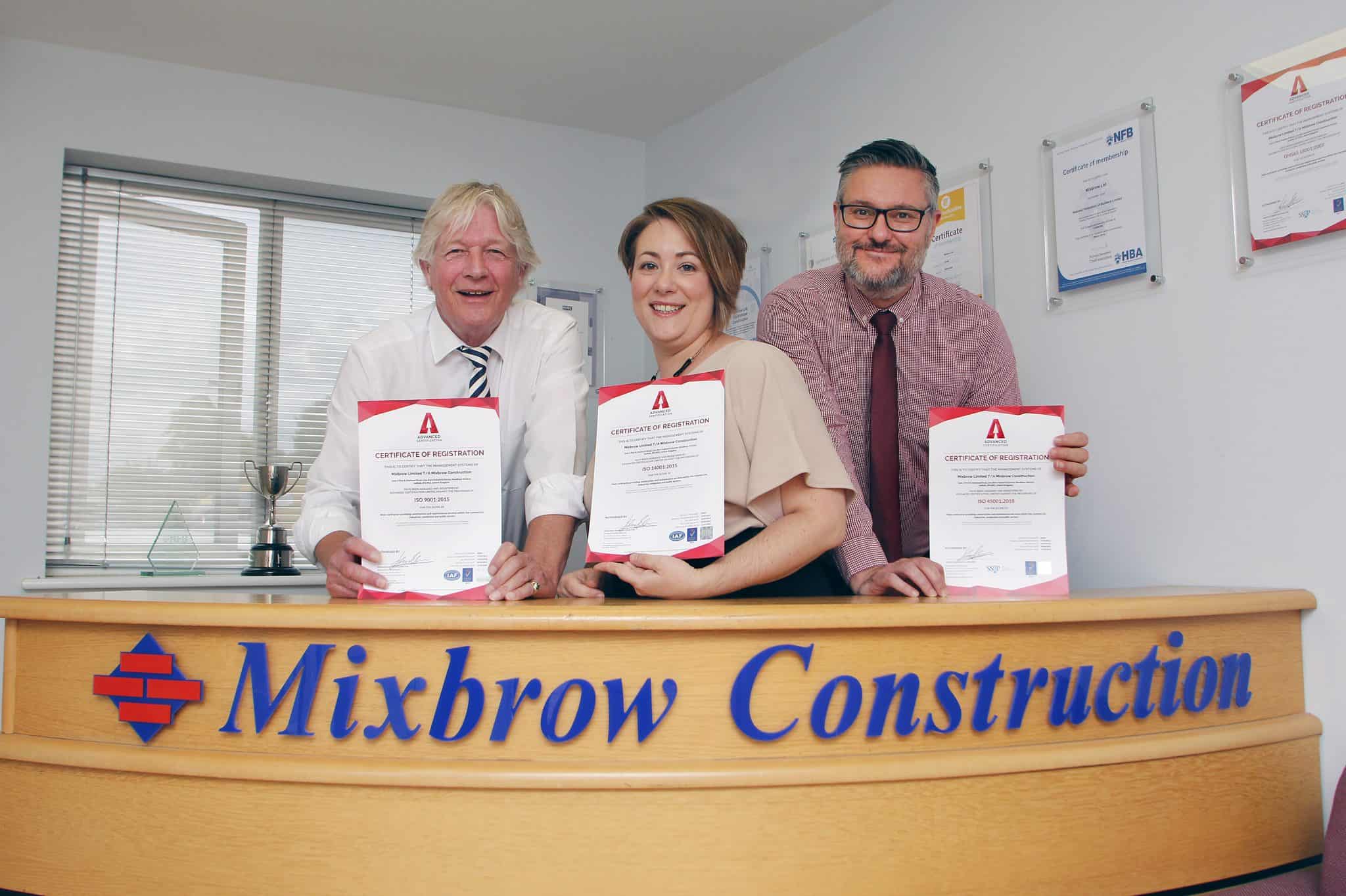 Happy team holding construction certificates at Mixbrow Construction office in Suffolk.