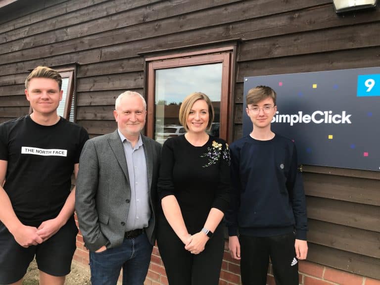 Suffolk Business team standing outside a wooden building with a Suffolk Business sign.