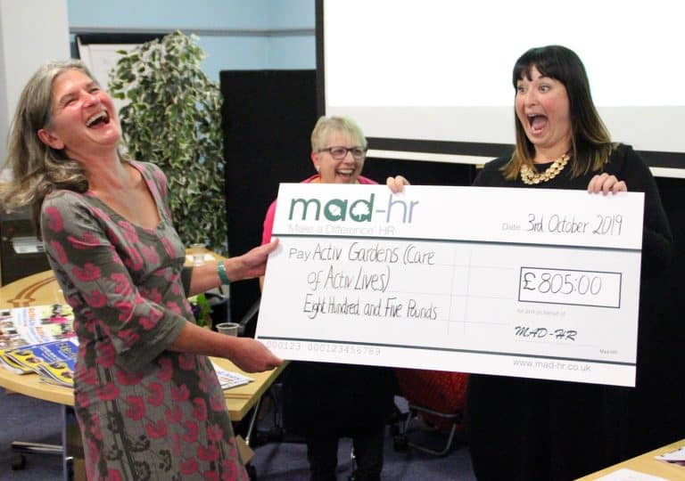 Women celebrating with a large cheque at Suffolk Business charity event.