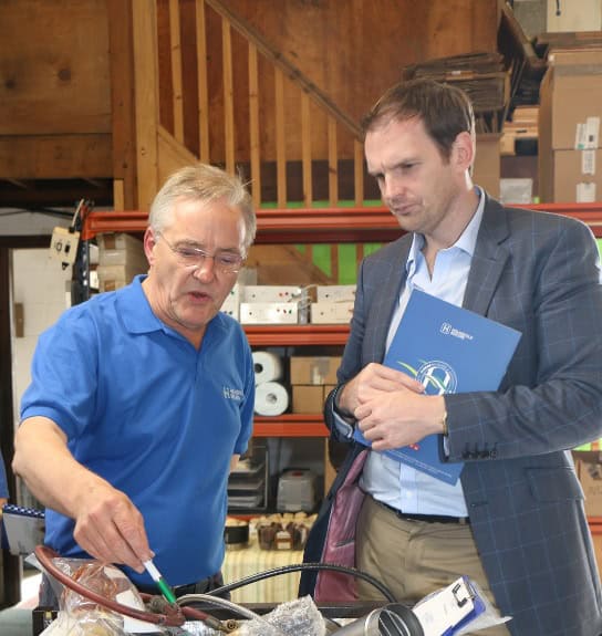 Efficient industrial discussion between two men in a warehouse setting, focusing on business operati.