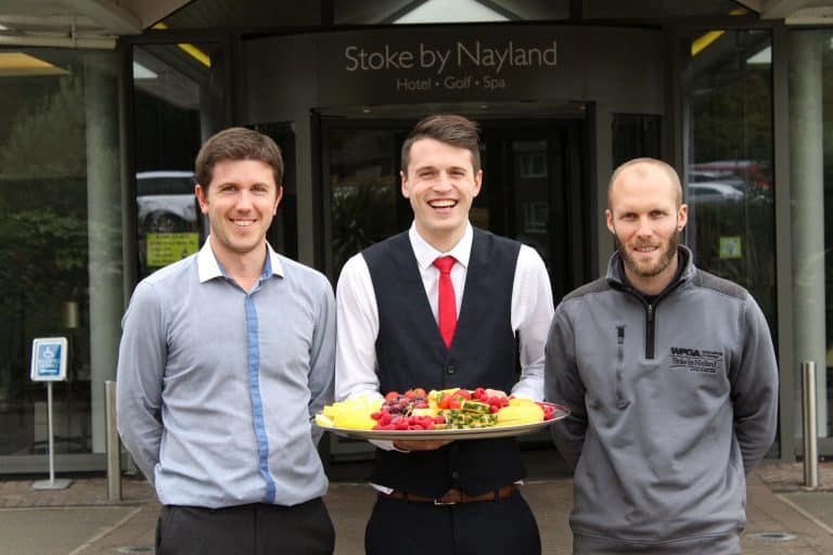 Friendly hotel staff at Stoke by Nayland presenting a fruit platter outside the hotel.