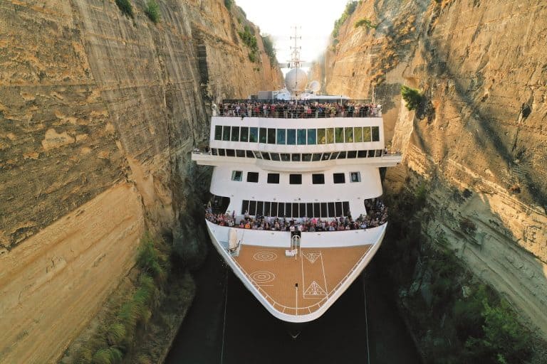 Luxury yacht navigating through a narrow canal with high cliffs on both sides.