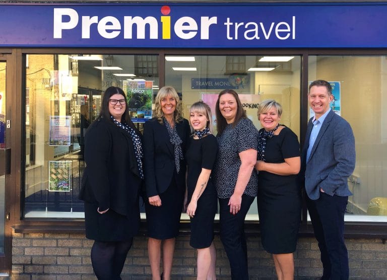 Suffolk Business travel team standing outside their office in front of Premier Travel.