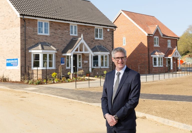 Modern residential housing development in Suffolk with a professional man in front.