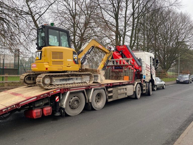 Heavy machinery being delivered on a flatbed truck in Suffolk, ready for construction project.