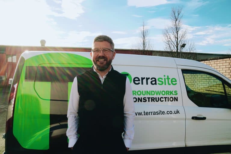 Business professional standing beside a TerraSite construction van in Suffolk.
