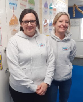 Two women in Suffolk Business hoodies smiling indoors.