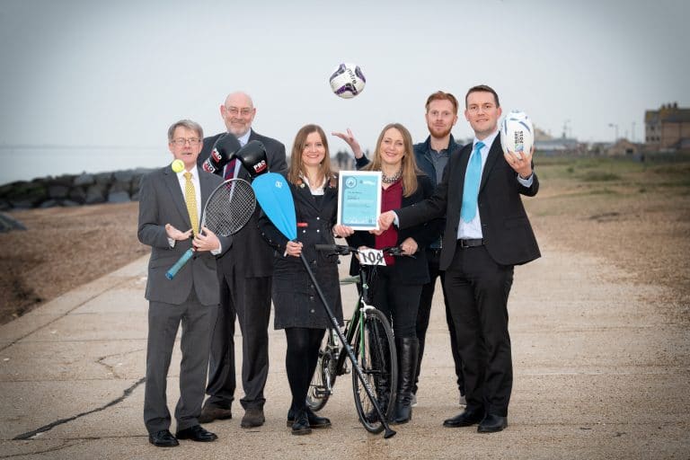 Suffolk Business team celebrating outdoors with sports equipment and a bicycle.