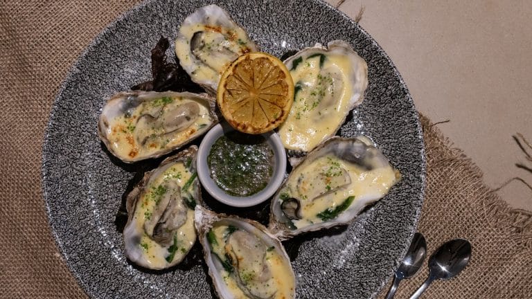 Delicious oysters served with lemon wedge and dipping sauce, perfect for seafood lovers.