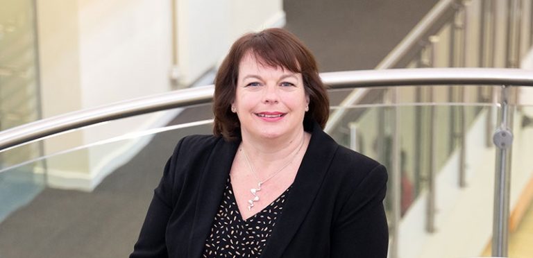 Suffolk Businesswoman smiling at a professional event in a modern office setting.