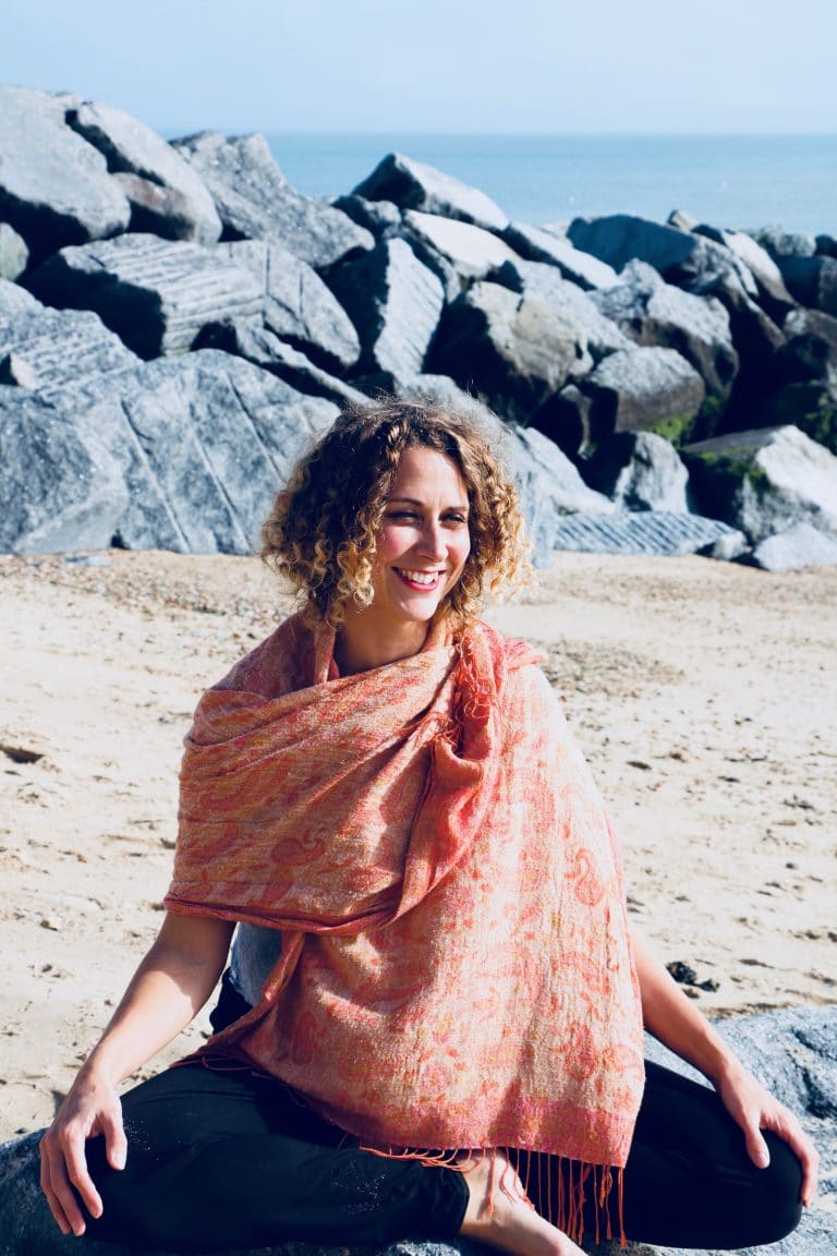 Relaxed woman practicing yoga on the beach in Suffolk, UK.