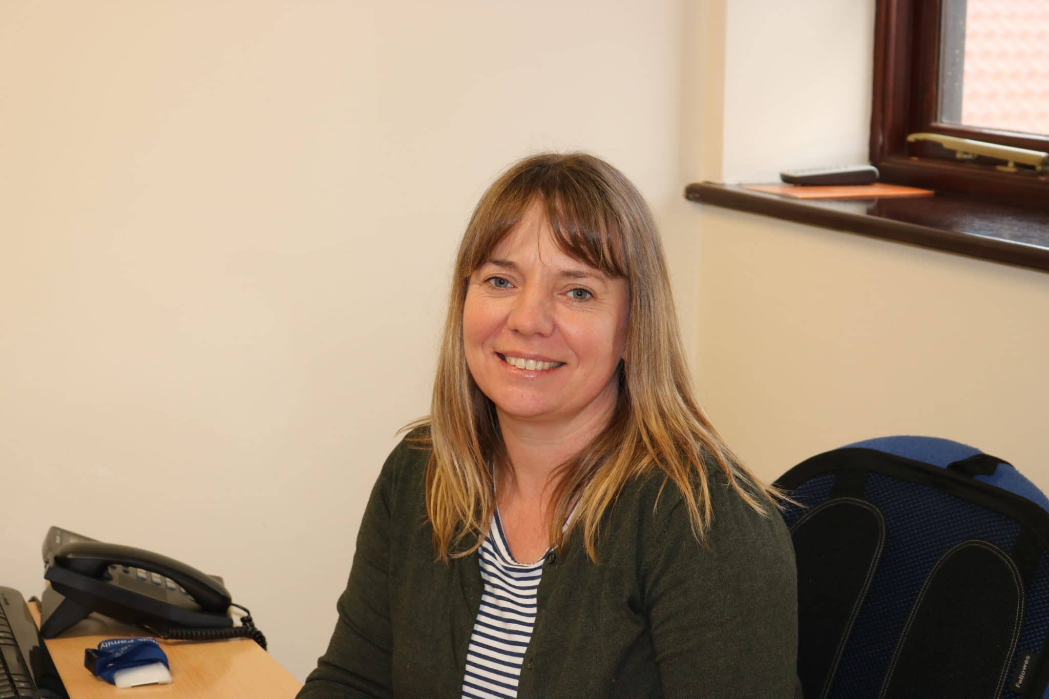 Woman smiling at her desk in a Suffolk business office setting.
