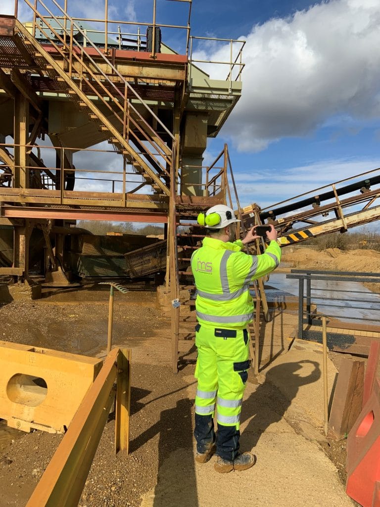 Construction worker in high-visibility gear inspecting industrial site in Suffolk.
