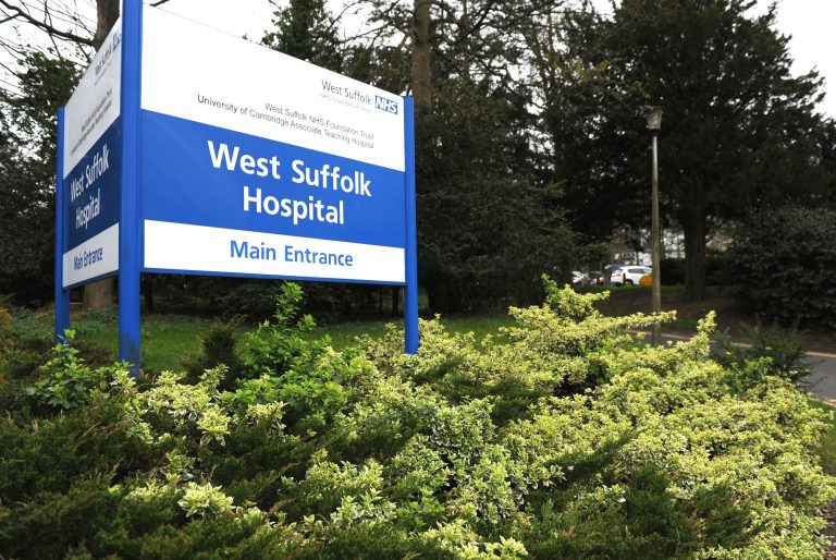 West Suffolk Hospital main entrance sign with greenery in Suffolk, UK.
