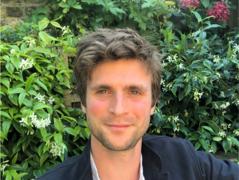 Young man smiling outdoors in a garden, representing Suffolk Business networking.