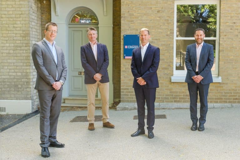 Professional Suffolk Business team standing outside office building in formal attire.