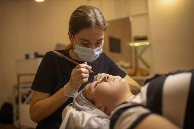 A woman receiving a facial treatment in a spa or clinic setting, wearing a face mask.