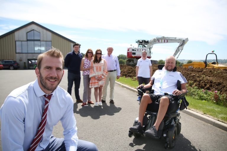 Business team visiting a construction site in Suffolk, including a man in a wheelchair.