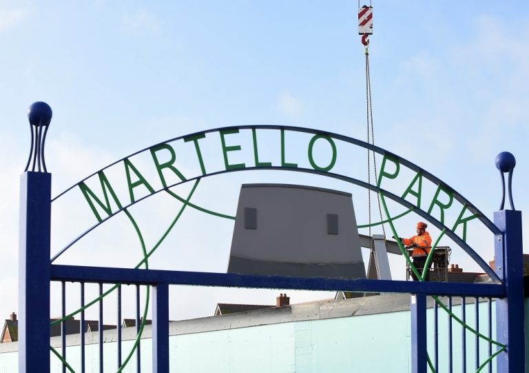 Entrance gate at Martello Park in Suffolk with worker installing signage.
