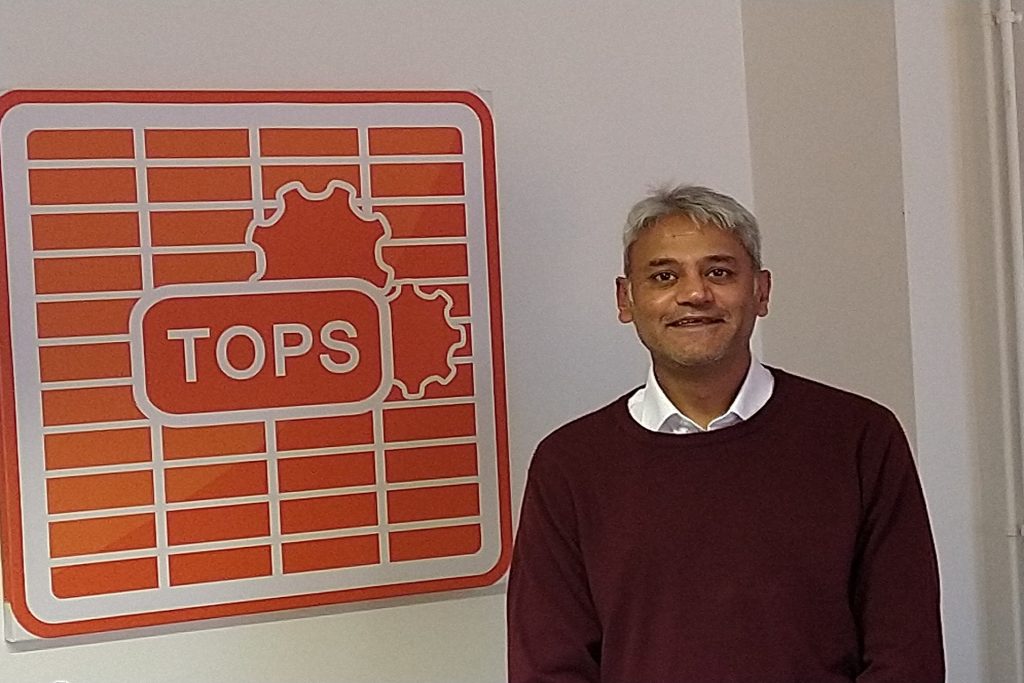 Business professional standing next to Suffolk Business logo in office setting.