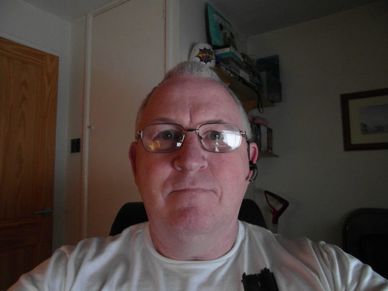 Close-up of a middle-aged man wearing glasses in an office setting.