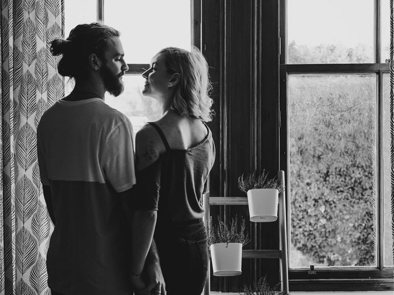 Young couple in love standing close inside a home, black and white photo.