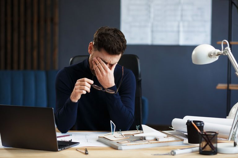 Business professional with stressed expression at desk in Suffolk office.