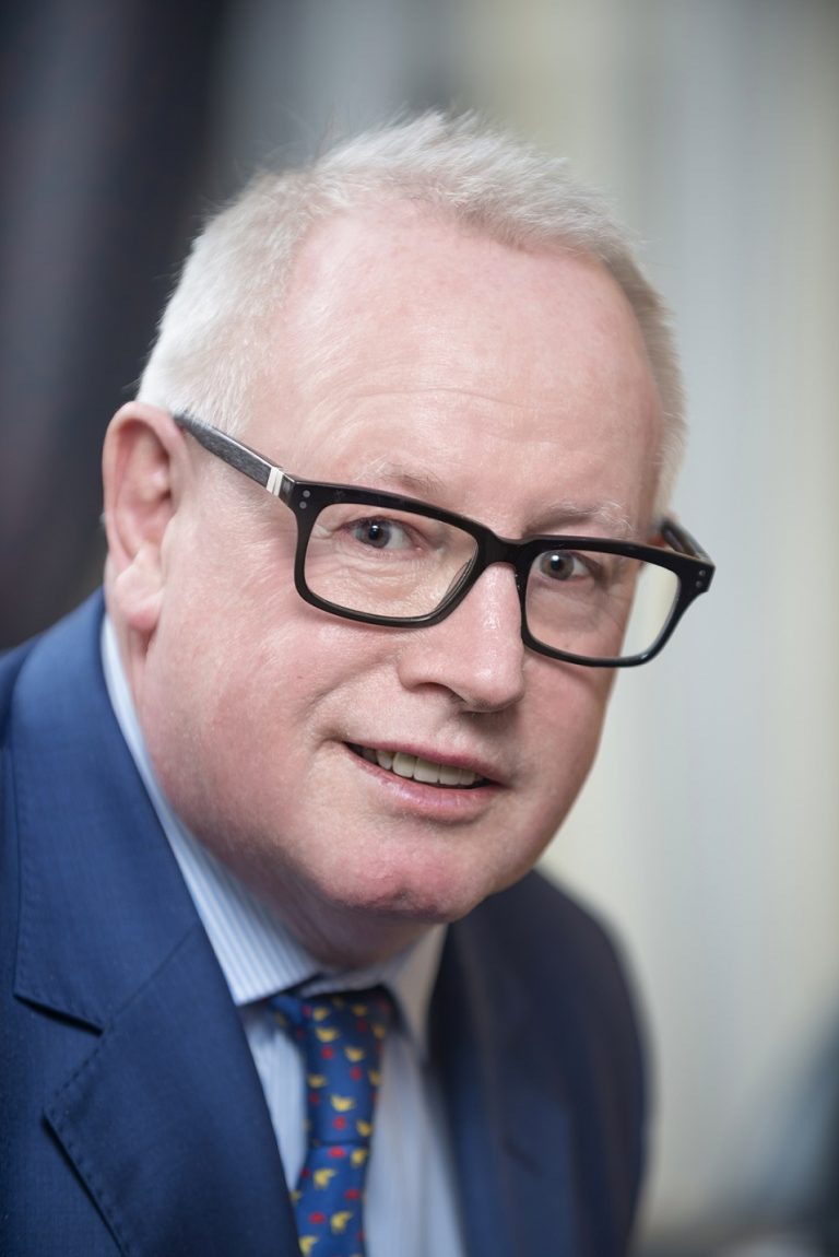 Business professional portrait of a mature man wearing glasses and a blue suit, representing Suffolk.