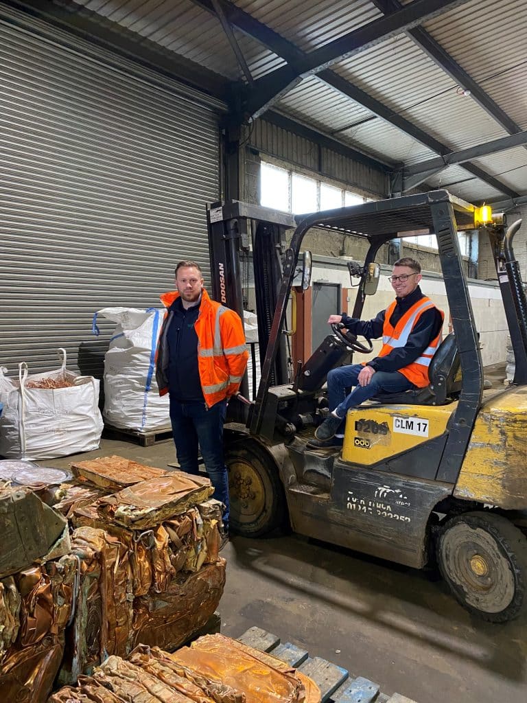 Warehouse workers operating forklift with timber in Suffolk industrial facility.