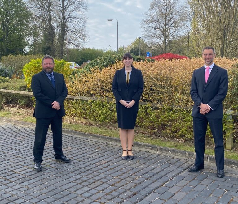 Business professionals standing outdoors in Suffolk, dressed in formal attire.