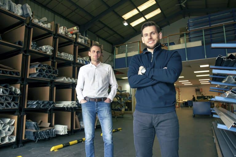 Two male workers in a Suffolk warehouse with metal shelves and industrial equipment.