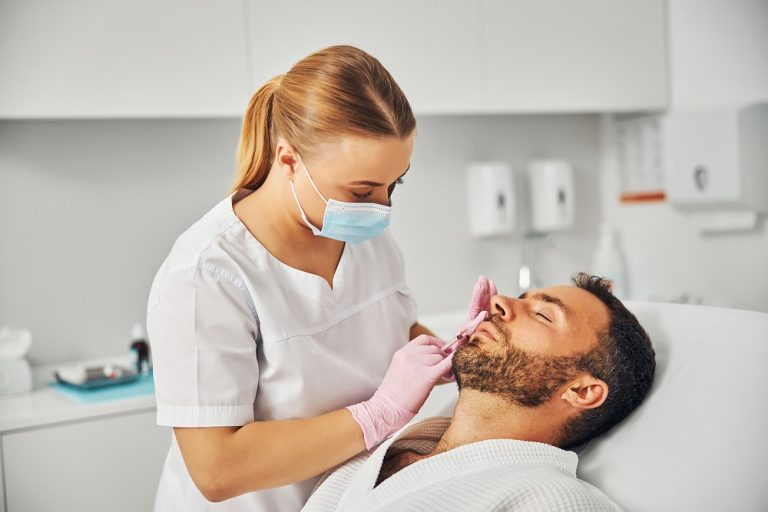 Dentist performing a dental check-up on a male patient in Suffolk clinic.