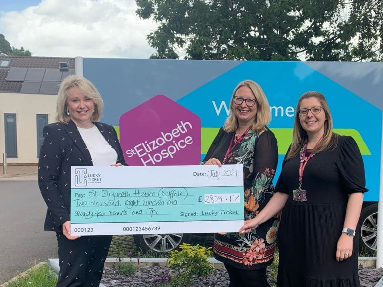 Women presenting a charity cheque for Suffolk Hospice at a community event.