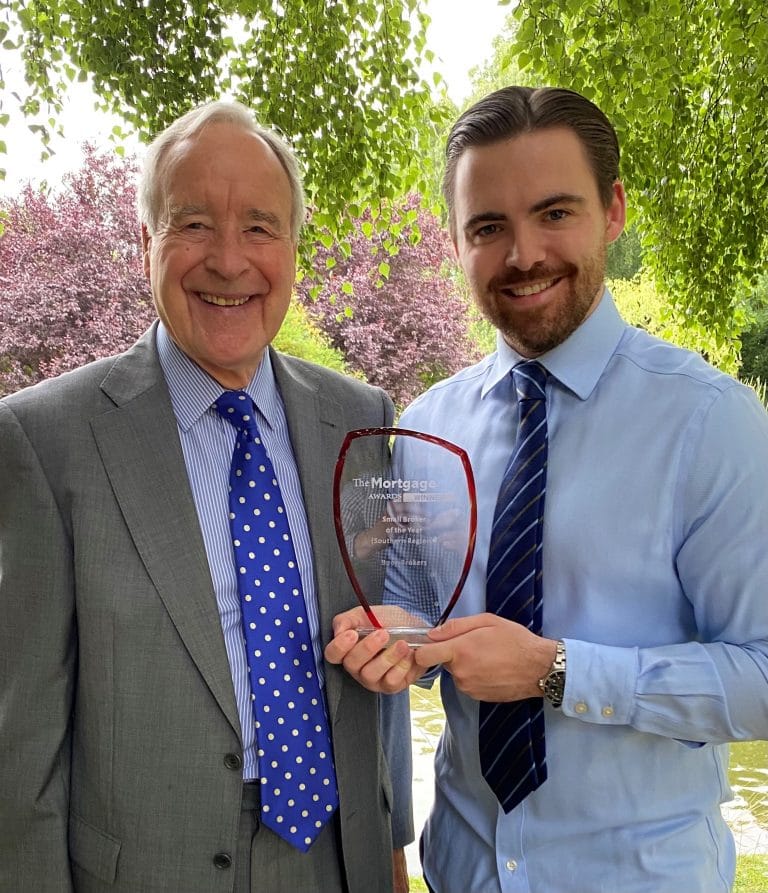 Two men smiling and holding a business award outdoors in Suffolk, celebrating success.