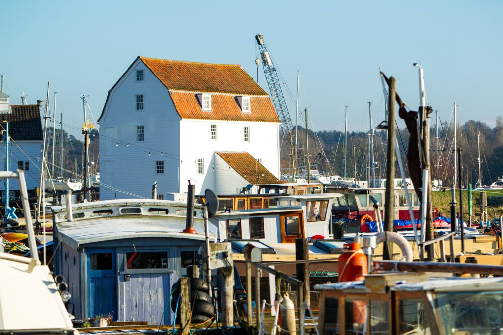 Marina with boats and a historic white house in Suffolk, showcasing maritime business and coastal li.