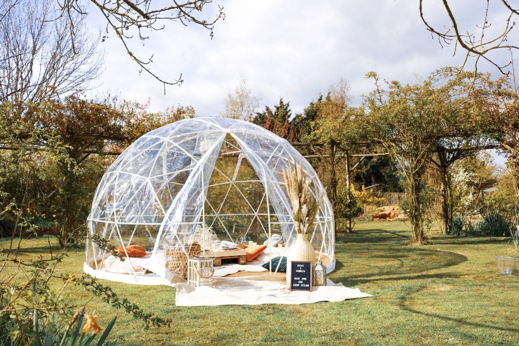 Outdoor glamping dome in Suffolk with cozy furnishings and scenic garden views.