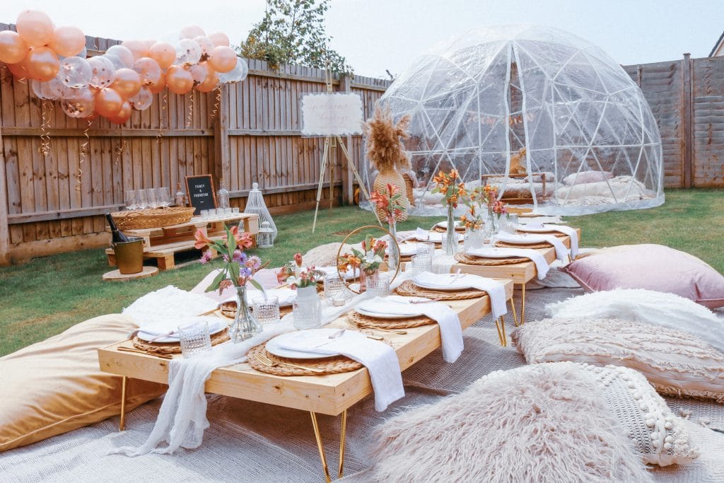 Elegant outdoor garden party with decorated table, cushions, and geodesic dome in Suffolk.