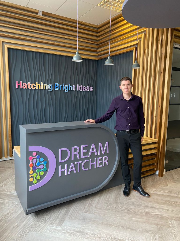 Business professional standing at Dream Hatcher reception with Hatching Bright Ideas sign.