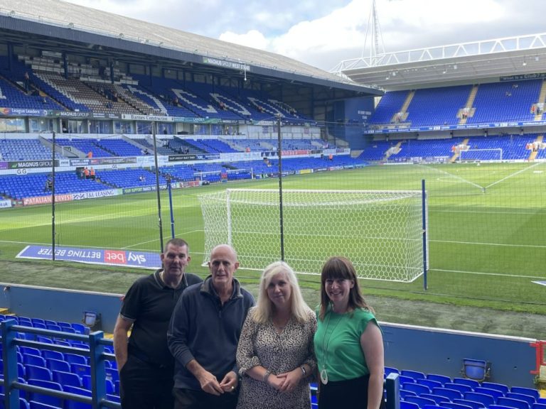Group of people touring a football stadium in Suffolk, showcasing local sports facilities.