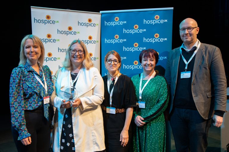 Hospice UK event with diverse professionals standing together in front of hospice banners.