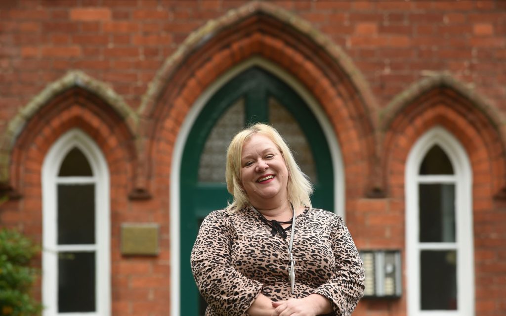 Businesswoman smiling at Suffolk networking event outside historic building.