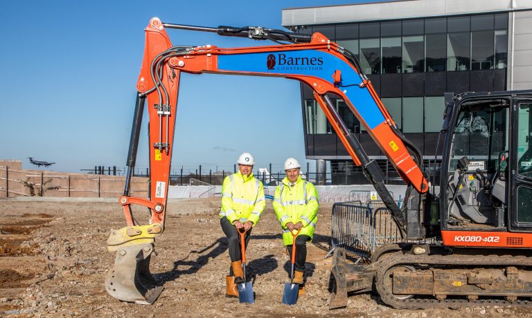Construction workers in high-visibility gear at Suffolk building site with excavator.