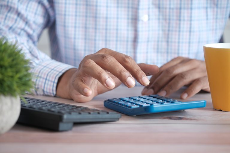 Businessperson calculating finances with calculator at desk.
