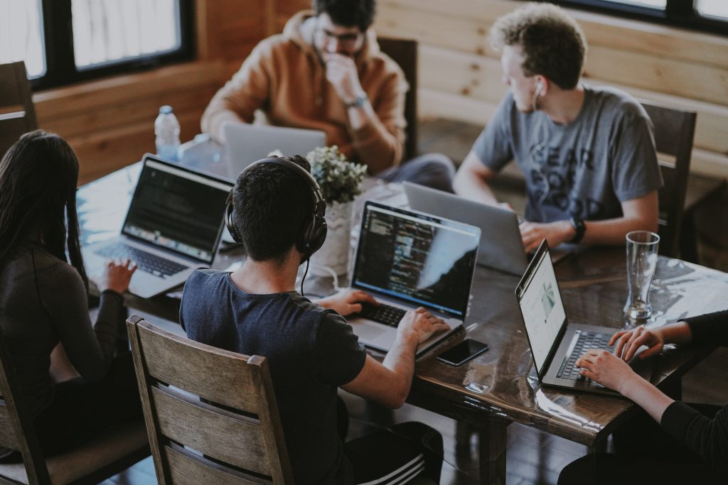 Team of young professionals collaborating on laptops in a modern office setting.