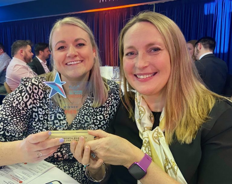 Two women smiling at Suffolk Business awards, holding a trophy.